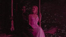 a woman in a white dress sits next to a woman in a black dress on a swing