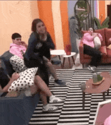 a group of people are sitting on couches in a living room with a checkered rug .
