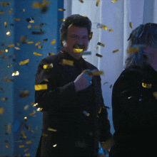 a man in a suit is standing in front of a wall of confetti