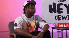 a man sits in front of a sign that says hey ( ew )