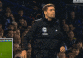 a man wearing an american express jacket stands in front of a crowd of people