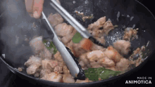 a person is using tongs to stir food in a pan that says made in animotica