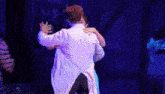 a man and a woman are hugging on a stage in front of a sign that says rebuilding