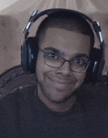 a man wearing headphones and glasses is smiling and looking at the camera