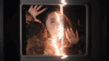 a woman in a fur coat is behind a glass with a light shining through it