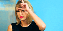 a woman is holding her hand to her forehead and pointing at it .