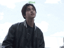 a young man wearing a black jacket with the word mint on the bottom right