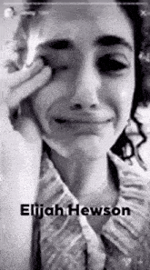 a woman is crying in a black and white photo with the name elijah hewson on the bottom .