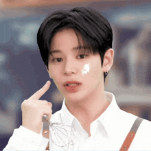 a young man with whipped cream on his face holds up his finger
