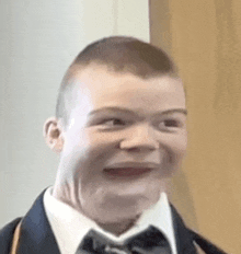 the boy is wearing a suit and tie and making a funny face .