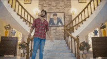 a man in a plaid shirt stands on a set of stairs in front of a picture of himself