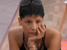 a woman with short black hair is laying down with her hand on her chin .