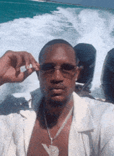 a man wearing sunglasses and a necklace is on a boat with a yamaha engine in the background