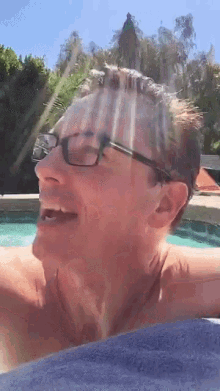a man wearing glasses is laying in a pool with his mouth open
