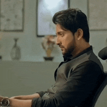 a man with a beard is sitting in a chair and looking down
