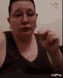 a woman wearing glasses and a black tank top is giving a thumbs up