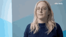 a blonde woman wearing glasses and a blue sweater with elite daily written on the bottom