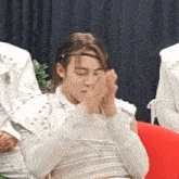 a man in a white shirt is sitting on a red couch clapping his hands .