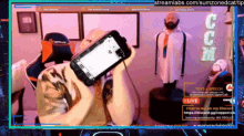 a man is holding a phone in front of a screen that says streamlabs.com/sumzonedcattip