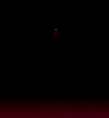 a person is standing in the dark with a red light coming out of their mouth .