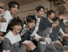 a group of young men in school uniforms are standing in front of a brick wall ..