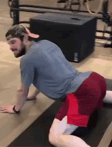 a man is doing a stretching exercise on a yoga mat in a gym .