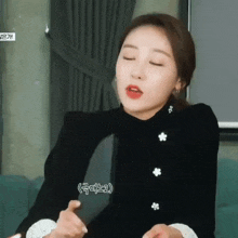a woman in a black dress is sitting on a couch with her eyes closed and making a funny face .