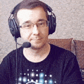 a man wearing glasses and headphones with a microphone looks at the camera
