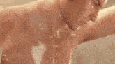 a shirtless man is taking a bath in a bathtub with water coming out of his armpits .