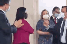 a group of people wearing masks are standing next to each other .