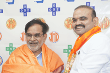 two men are posing for a picture in front of a wall that says one on it