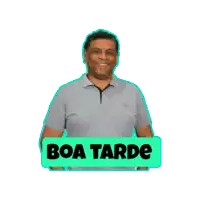 a man in a grey shirt stands next to a sign that says " boa tarde "