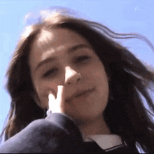 a close up of a woman 's face with her finger on her nose .