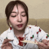 a woman wearing a christmas pajamas is eating with chopsticks