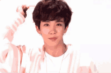 a young man with curly hair is holding a pencil in his hand and making a funny face .