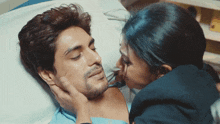a woman kisses a man 's face in a hospital bed