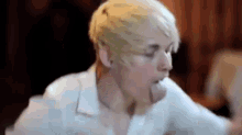 a woman with short blonde hair is eating a piece of food from a plate .