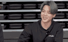 a young man with gray hair is wearing a black fila sweatshirt .