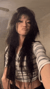 a woman with long dark hair is taking a selfie in a room .