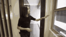 a woman in a black shirt is pointing at a window in a room made by animatica