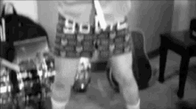 a person 's feet are shown in a black and white photo with a guitar and a backpack in the background