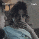 a woman covering her mouth with her hand while watching nine perfect strangers