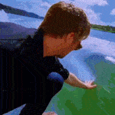 a man in a black shirt is touching a green surface
