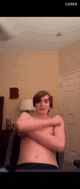 a man without a shirt is sitting in a room with a letter b on the wall