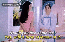 two women are standing next to each other and one of them is asking the other if she would like some tea .