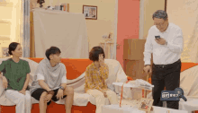 a group of people are sitting on a couch and a man is looking at a cell phone