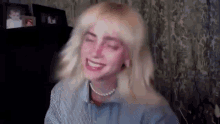 billie eilish is wearing a striped shirt and a pearl necklace while laughing .