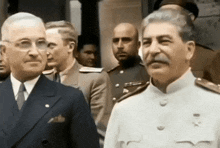 a man in a suit and tie stands next to another man in a white uniform