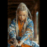 a woman in a kimono is holding a sword in her hands .