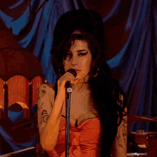 a woman singing into a microphone while wearing a red dress